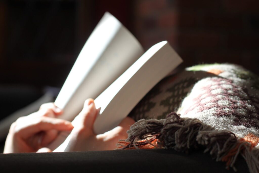 a person’s hands holding a book open on their lap