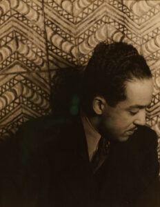 Sepia photo of Langston Hughes against patterned curtain