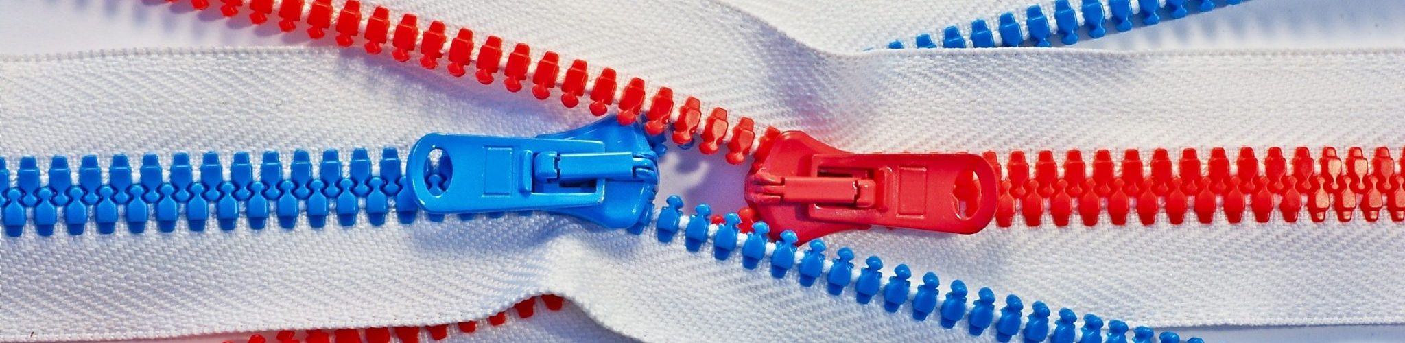 two zippers, one red and one blue, unattached to anything and crossed, zipping into each other