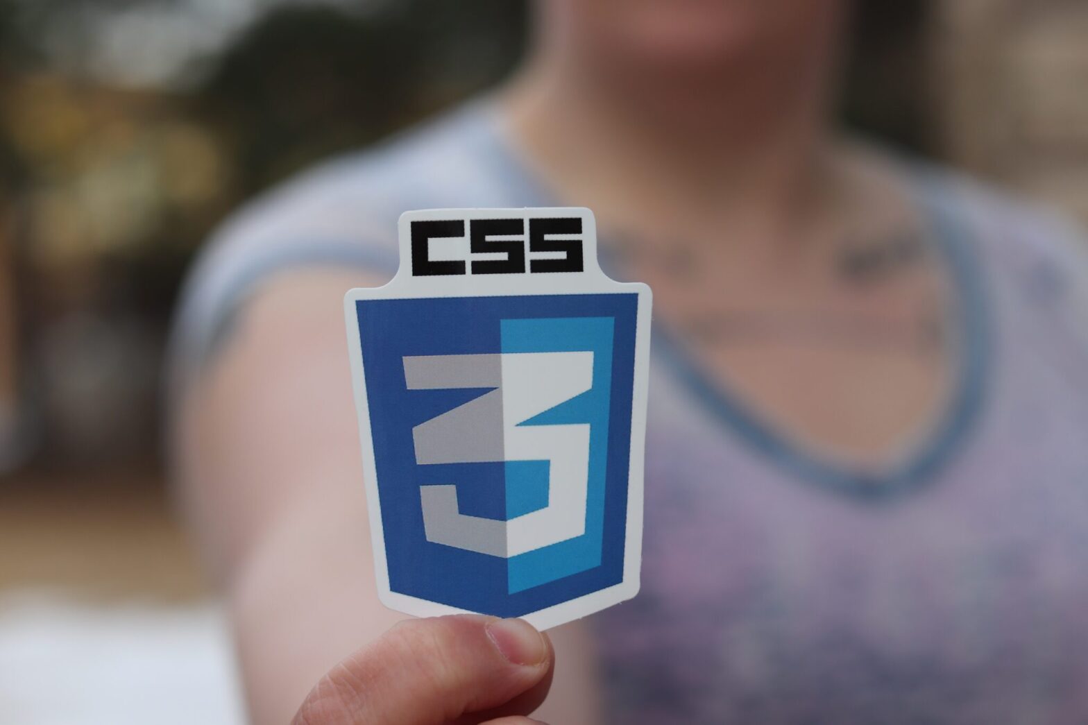 person holding sticker of CSS3 logo